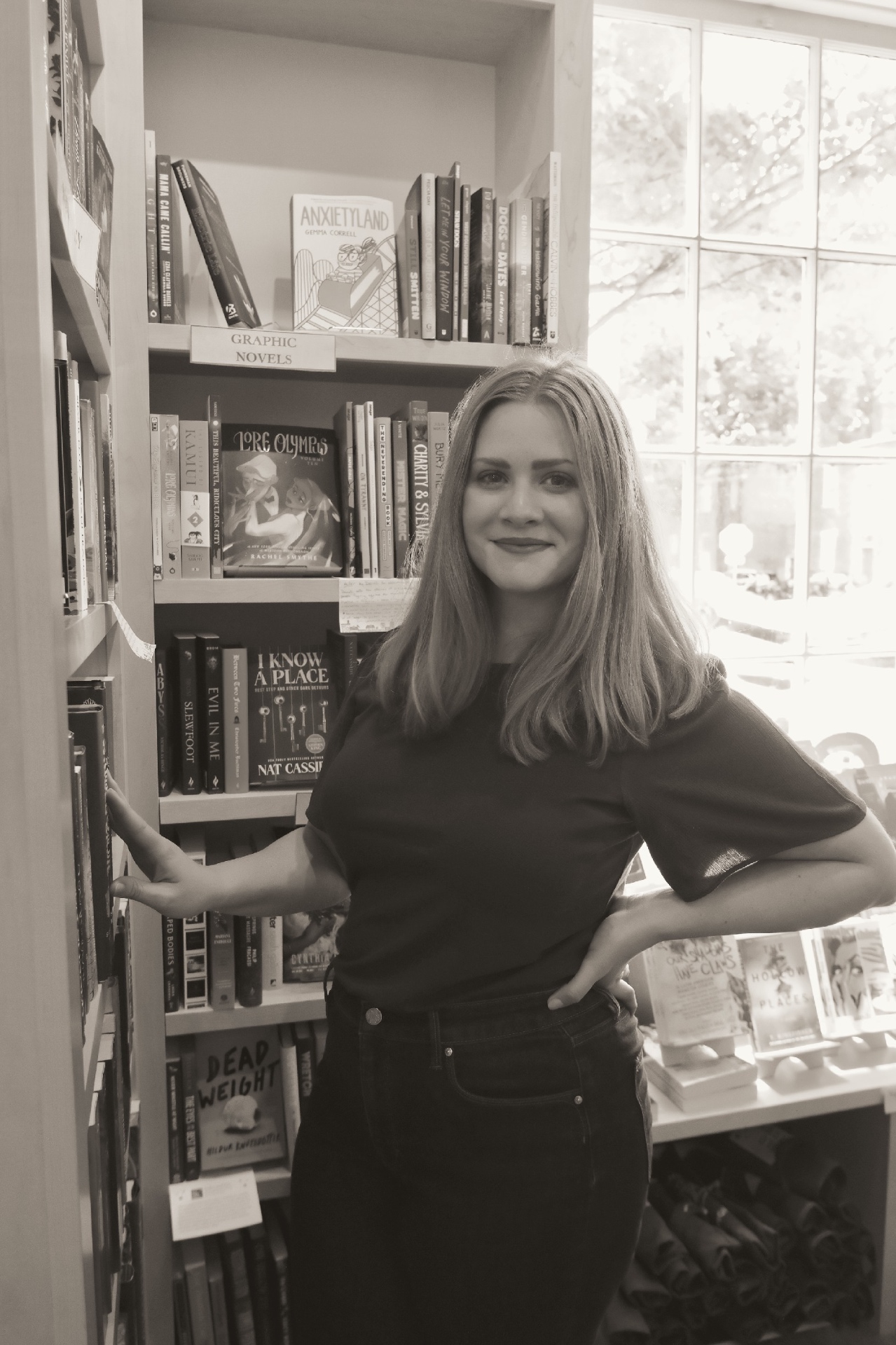 Karen, book coach for speculative fiction writers, standing in front of a bookshelf